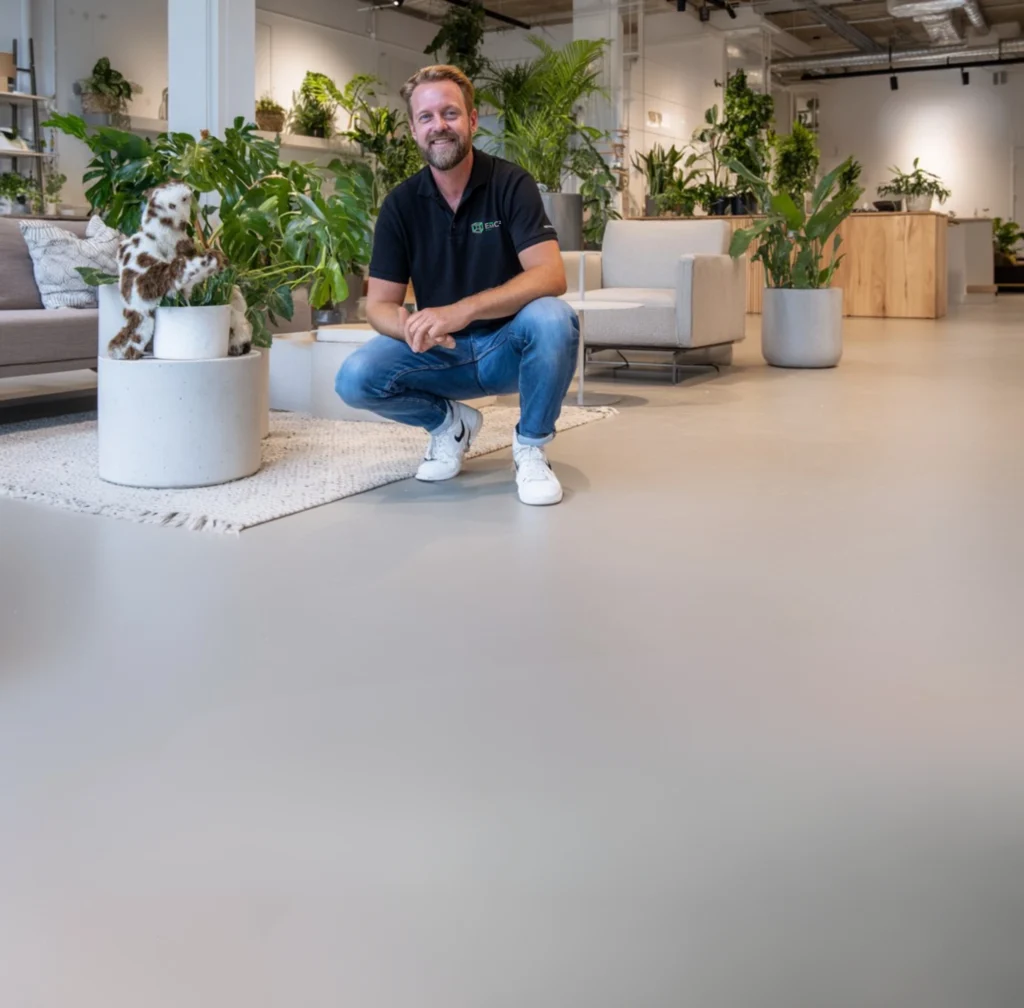 Facilitair medewerker van E=MC² Facilitair in een moderne kantoorruimte met een strak afgewerkte gietvloer.